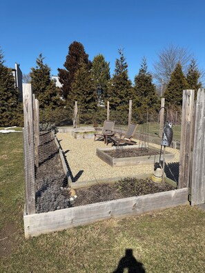 A fenced outdoor area with a wooden bench and a fire pit. - Waterfront Farm Cottage close to Newport, Boston, (Tiverton)