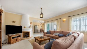 A living room with a television, sofa, coffee table, fireplace, and a dining area in the background. - Villa 'Monte Lemos  35' with Sea View, Wi-Fi and Air Conditioning (Luz)