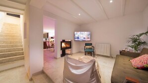 Ein Wohnzimmer mit Kamin, Fernseher, Sofa und einer Treppe, die in einen anderen Raum führt.