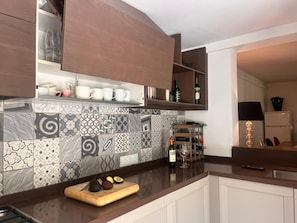 Een moderne keuken met betegelde spatwand, houten kastjes en een aanrecht met snijplank en avocado.