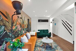 Ein modernes Wohnzimmer mit einer Couch, einem Couchtisch und einer großen Pflanze.