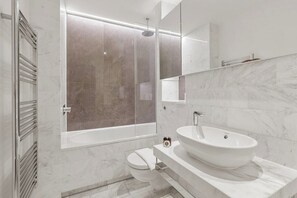 Une salle de bain moderne avec une douche à parois de verre, un lavabo blanc et des toilettes.