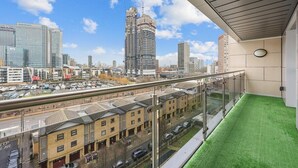 A balcony with a view of a cityscape, including a tall building under construction. - 2-bedroom apartment near Canary Wharf (London)