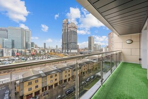 A balcony with a view of a cityscape, including a tall building under construction. - 2-bedroom apartment near Canary Wharf (London)