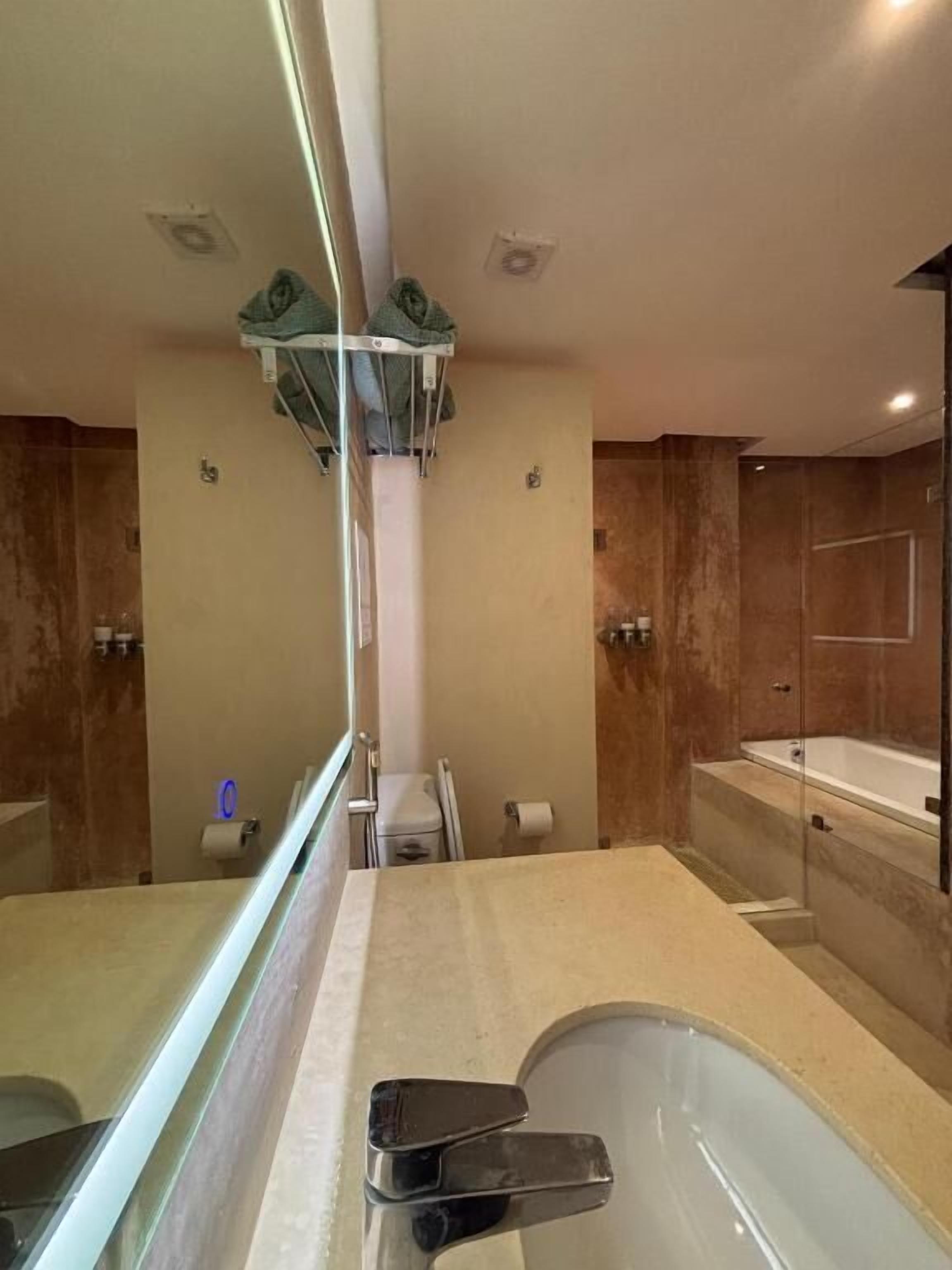 A modern bathroom with a glass-enclosed shower, a bathtub, and a toilet.