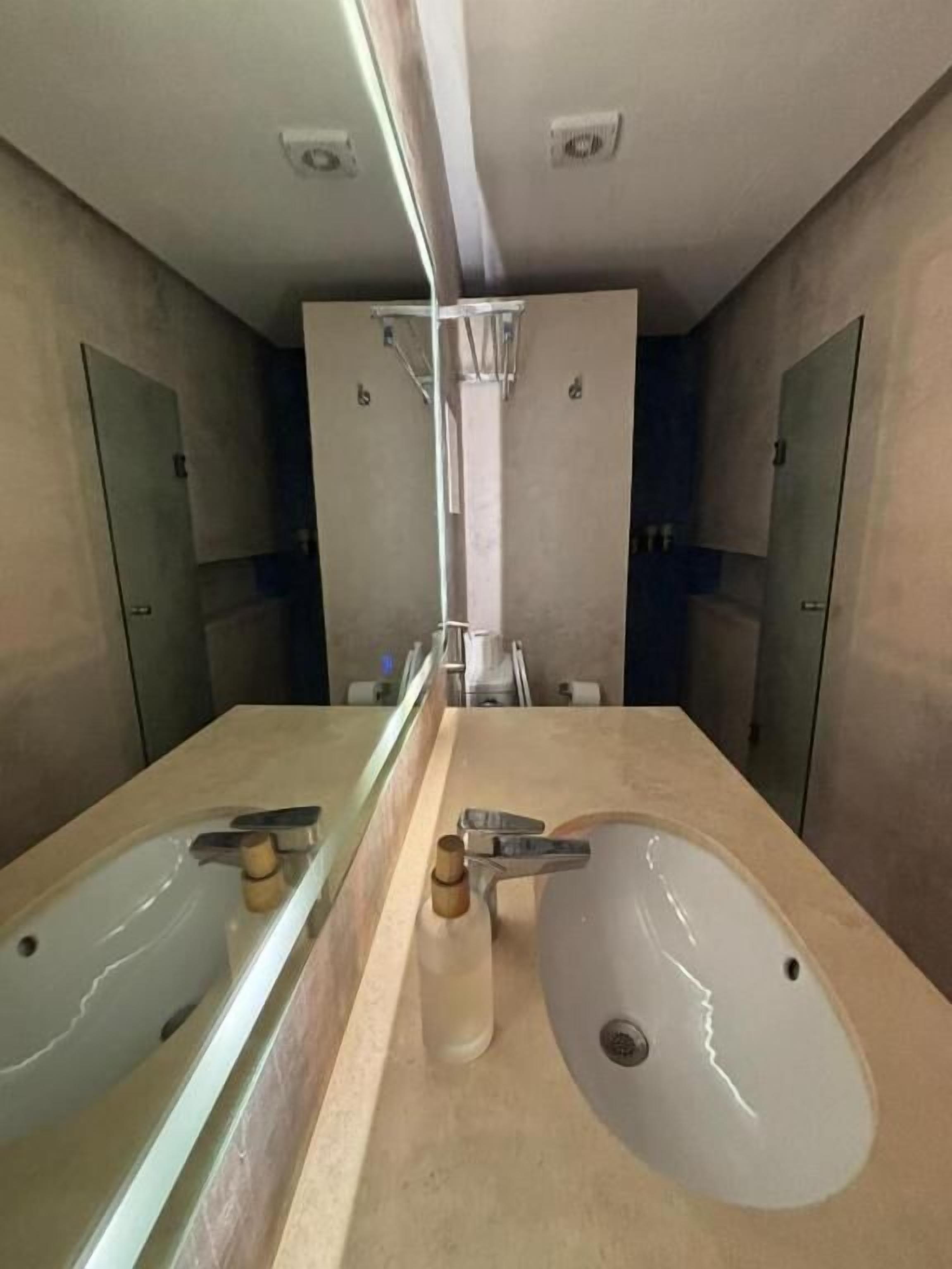 Un baño moderno con dos lavamanos, un espejo grande y un perchero para toallas.