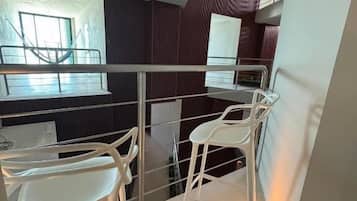 Un interior moderno con comedor, sillas blancas y barandilla de vidrio.