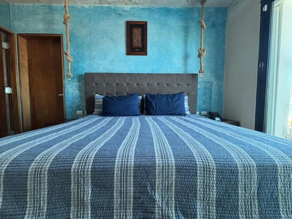 A bedroom with a large bed, a wooden door, and a blue wall.