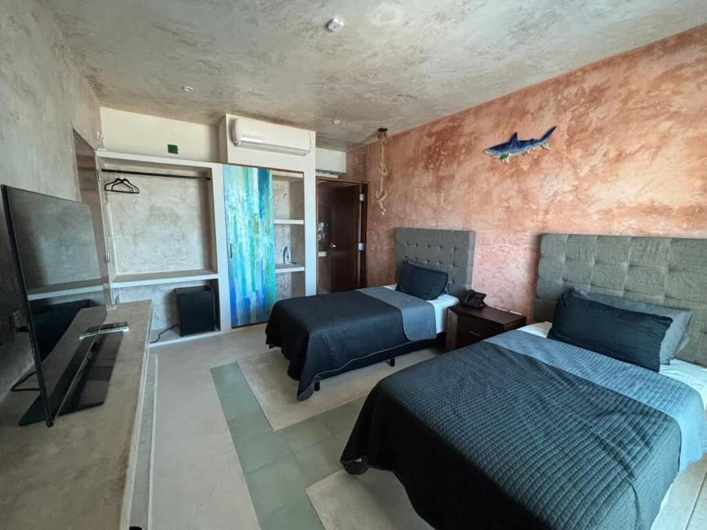 Habitación de hotel con dos camas, televisión, armario y baño.