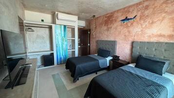 Habitación de hotel con dos camas, televisión, armario y baño.