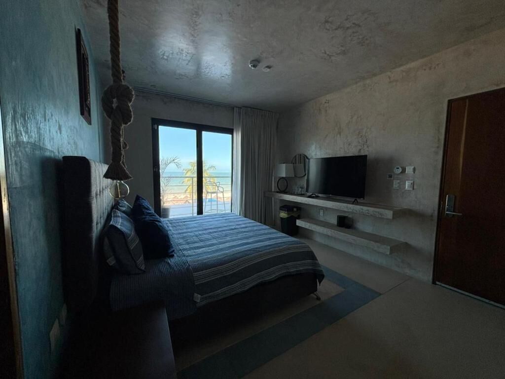 A bedroom with a bed, a TV, and a view of the outdoors.