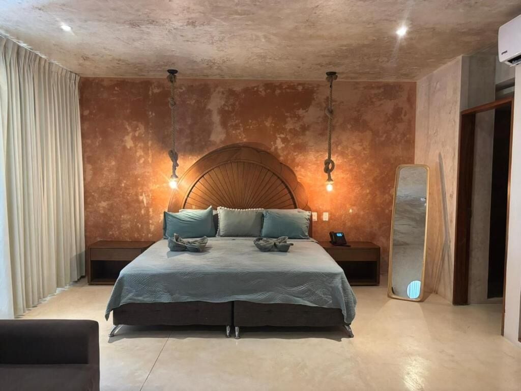 Un dormitorio con una cama grande, dos mesitas de noche, una lámpara de pared y un espejo.