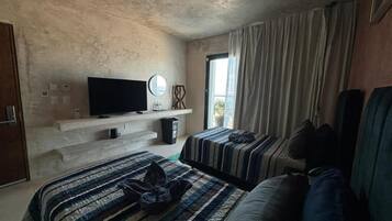 Une chambre d’hôtel avec deux lits, une télévision, une petite table et une fenêtre avec des rideaux.