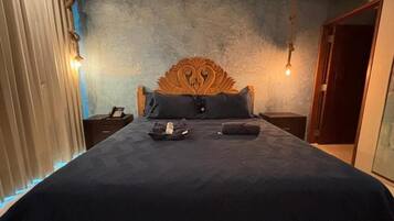 Ein Schlafzimmer mit einem großen Bett, einem Holzkopfstück, einem Nachttisch mit einer Lampe und einem Beistelltisch mit einem Telefon.