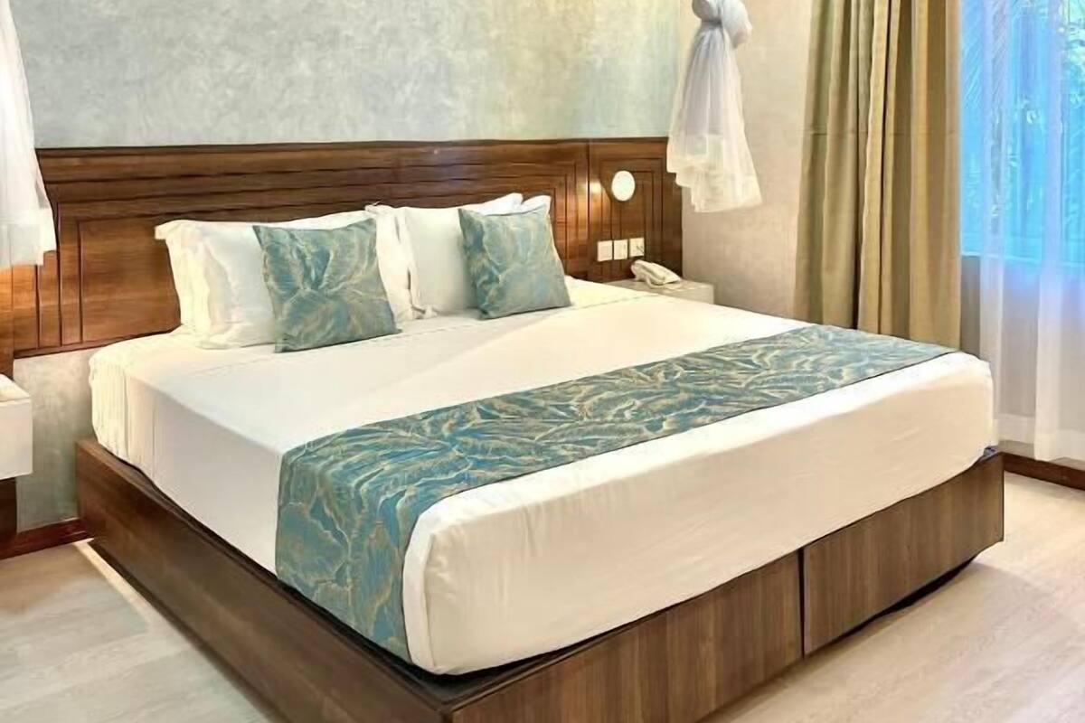 Een hotelkamer met een groot bed, een houten hoofdeinde en uitzicht op het omliggende landschap.