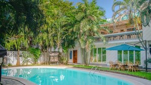 Une piscine entourée de palmiers et un bâtiment doté d’un balcon.