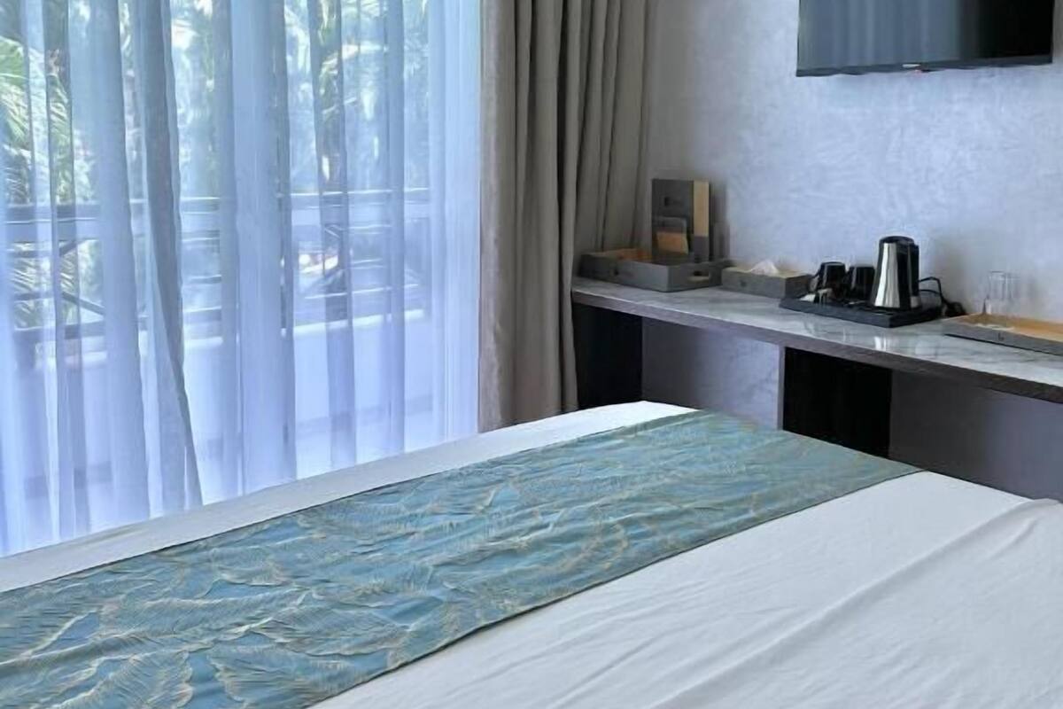 Een hotelkamer met een bed, een bureau, een televisie en een raam met gordijnen.