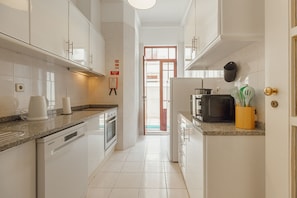 A modern kitchen with white cabinets, a dishwasher, an oven, a microwave, and a sink. - CITY CENTER TERRACE APARTMENT by VACATIONY (Oporto)