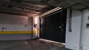 Een ondergrondse parkeergarage met betonnen vloeren, een gele streep op de muren en een gesloten garagedeur.