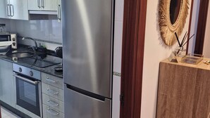 Een moderne keuken met roestvrijstalen apparatuur, houten kastjes en een decoratieve spiegel.