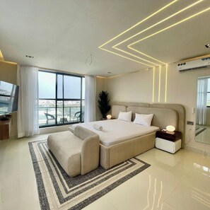 A modern bedroom with a large bed, a TV, and a balcony view. - Home N Luxe Apartment (Lekki)