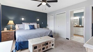 Ein Schlafzimmer mit Bett, Nachttisch, Lampe und Deckenventilator.