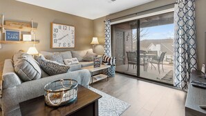 Ein modernes Wohnzimmer mit einer Couch, einem Couchtisch und einem großen Fenster mit Blick auf eine Terrasse.