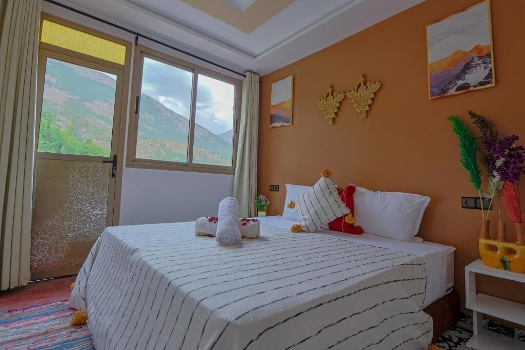 Una habitación de hotel con una cama grande, una ventana con vistas a la montaña y un adorno en la pared.