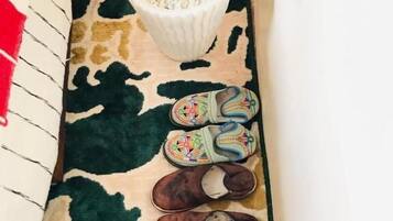Slipper und Pflanze auf einem gemusterten Teppich.