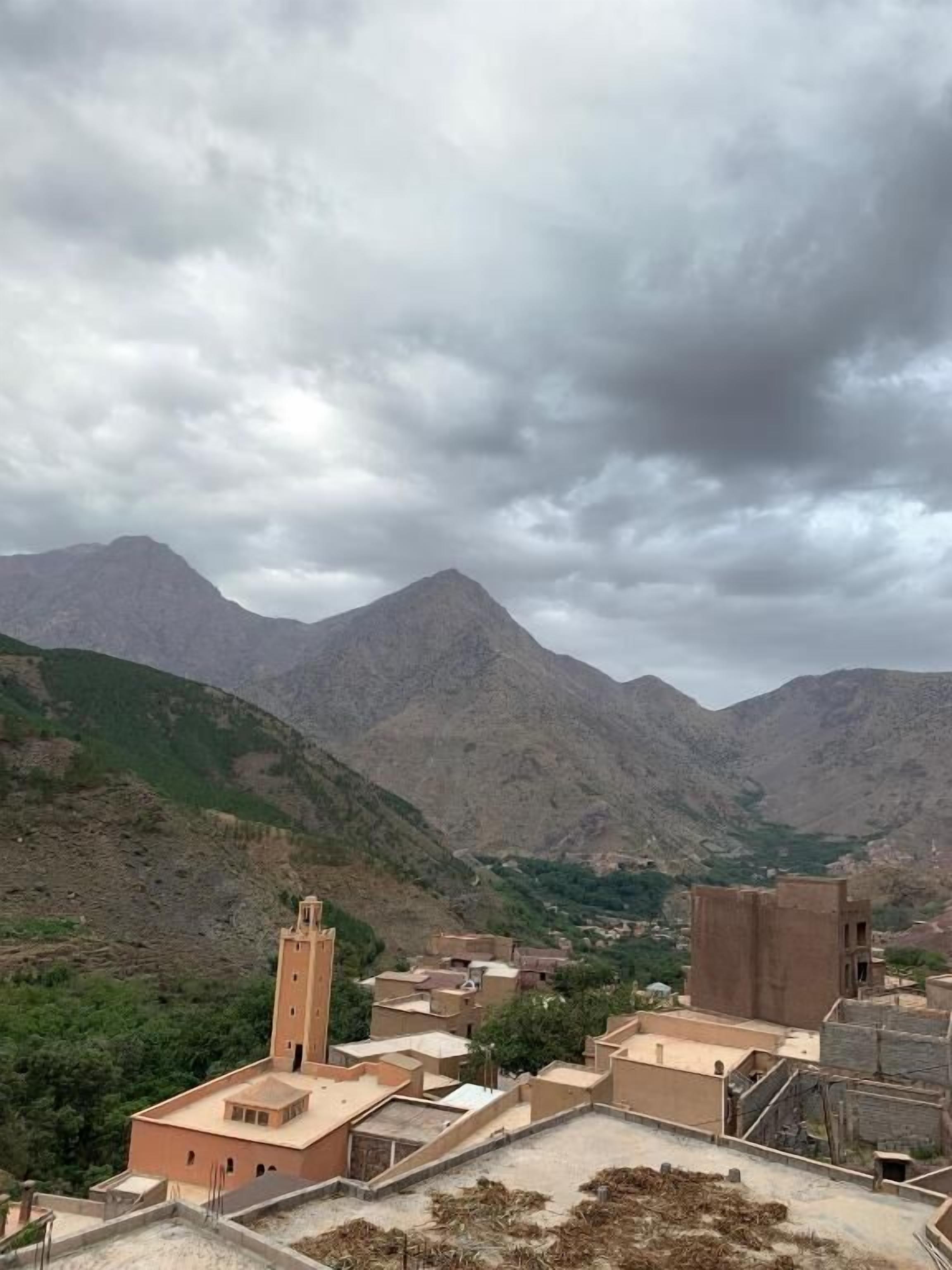 A mountainous landscape with a village featuring traditional architecture and a prominent minaret.