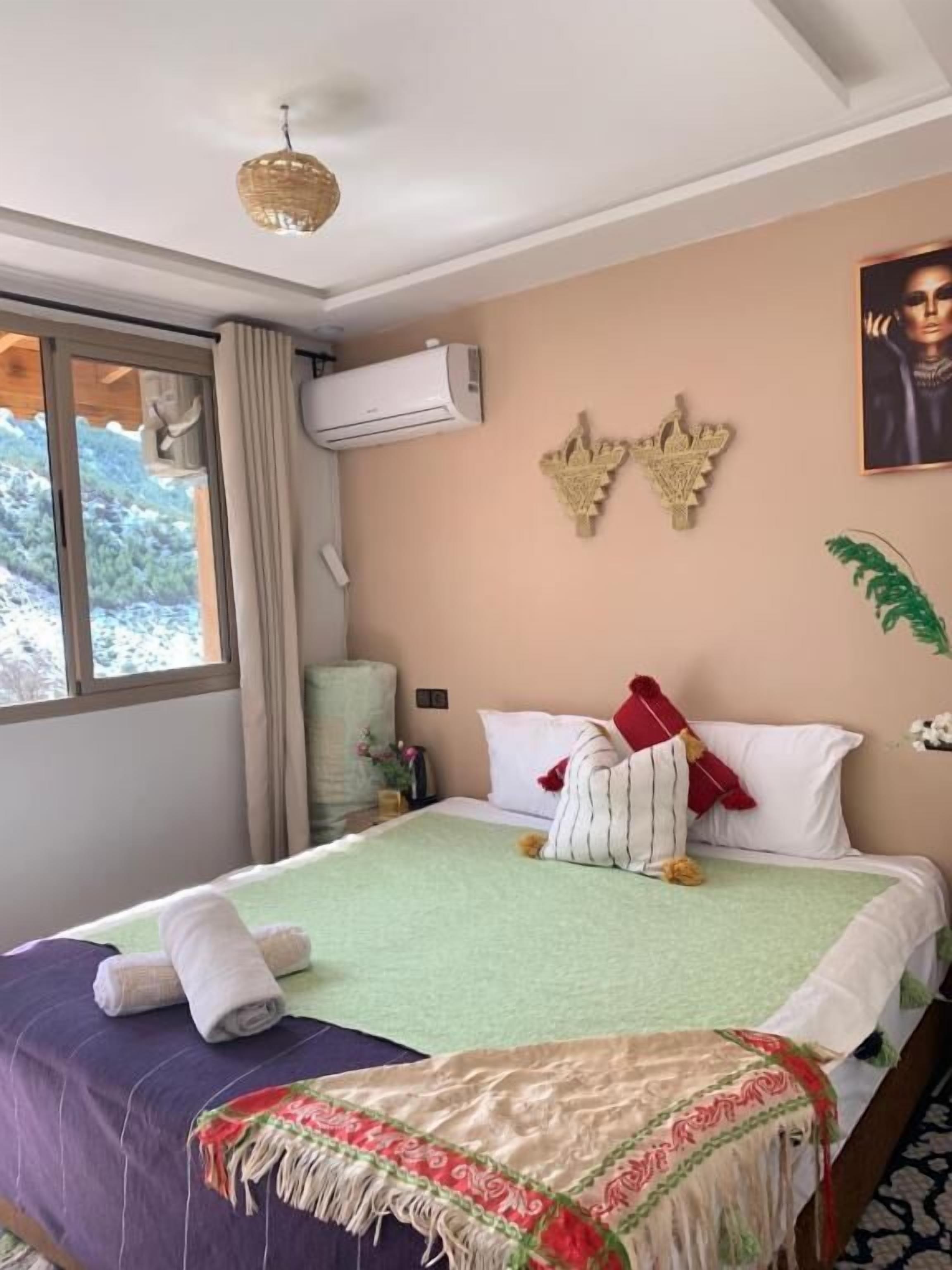 Habitación de hotel con cama, ventana, equipo de aire acondicionado y un adorno en la pared.