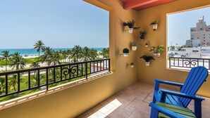 A balcony with a view of the beach, potted plants, and a blue chair. - The Netherland R5B on OceanDr (Miami Beach)