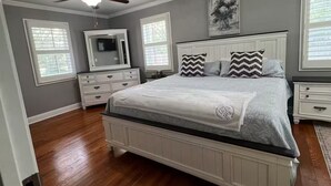 A bedroom with a large bed, a dresser, a vanity, and a ceiling fan. - Family Friendly home down from the lake, just minutes to a dock and downtown! (Guntersville)
