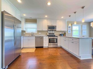 A kitchen with white cabinetry, stainless steel appliances, a microwave, and a toaster.