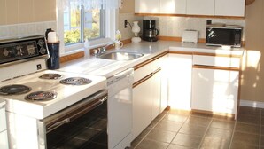 Een keuken met een fornuis, spoelbak en magnetron.