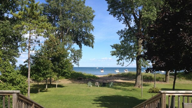 Een terras met uitzicht op een strand en de oceaan, omgeven door bomen.