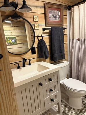 Een houten interieur met een wastafel, spiegel, handdoekhouder en toilet.