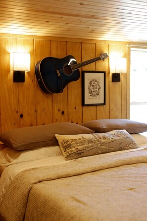 A room with a bed, a guitar, two wall-mounted lamps, and a framed picture. - The Gathering Stables - Country charm on a horse farm, minutes from Nashville (Goodlettsville)