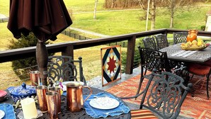 An outdoor patio with a round table set for dining, surrounded by chairs with striped cushions. - Working Horse Ranch Retreat – 2 Bedrooms, Fire Pit, 20 Min to Downtown Nashville (Goodlettsville)
