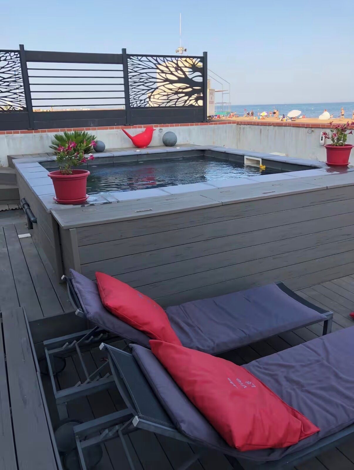 Een dakterras met een zwembad, ligbedden en een decoratieve hek.