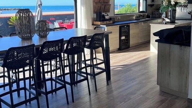 A modern kitchen with a large island, a dining area with a view of the ocean, and a spacious living area with a large window overlooking the sea. - Ma vie là - House on the beach (Valras-Plage)