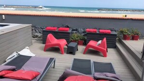 A rooftop terrace with lounge chairs, a small table, and a hot tub. The terrace overlooks a beach with a rocky breakwater and the ocean. - Ma vie là - House on the beach (Valras-Plage)