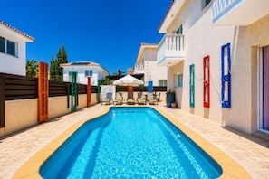 A swimming pool with a tiled deck, a covered seating area, and a building with balconies. - Villa Chromata - Three Bedroom Villa, Sleeps 7 (Pernera)