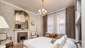 Une chambre avec un grand lit, une cheminée, un bureau et un miroir.
