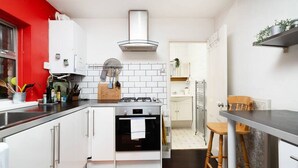 A compact kitchen with white cabinets, a gas stove, and a built-in oven. - Chic One-Bedroom Apartment in London (London)