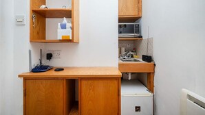 Une petite cuisine équipée comprenant un four à micro-ondes, un évier et des placards en bois.