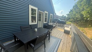 A deck with a table and chairs, a covered seating area, and a view of a backyard. - Charming 3-bedroom completely remodeled country house in Tappahannock with AC (Tappahannock)