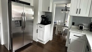 A modern kitchen with white cabinetry, a stainless steel refrigerator, and a built-in coffee maker. - Charming 3-bedroom completely remodeled country house in Tappahannock with AC (Tappahannock)