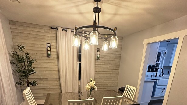 A dining room with a wooden table and chairs, a chandelier, and a view into the kitchen. - Charming 3-bedroom completely remodeled country house in Tappahannock with AC (Tappahannock)