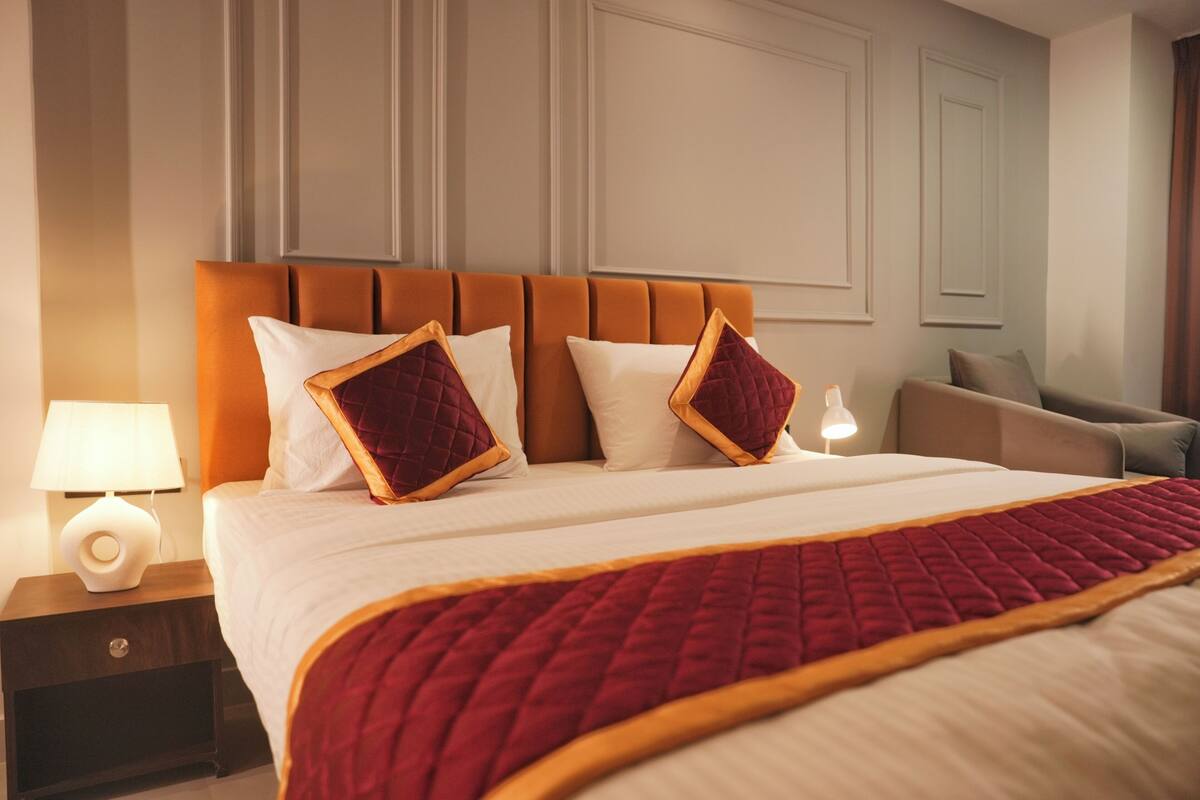 Une chambre d’hôtel avec un lit, une table de chevet, une lampe et une chaise.